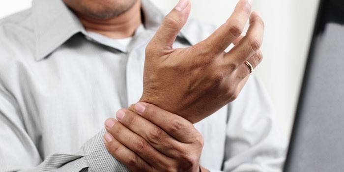 El hombre sostiene su mano sobre su muñeca