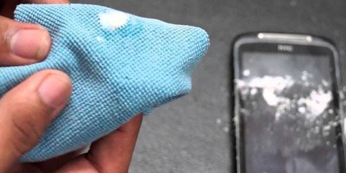 Tkanina s látkou v rukách a smartphone na stole