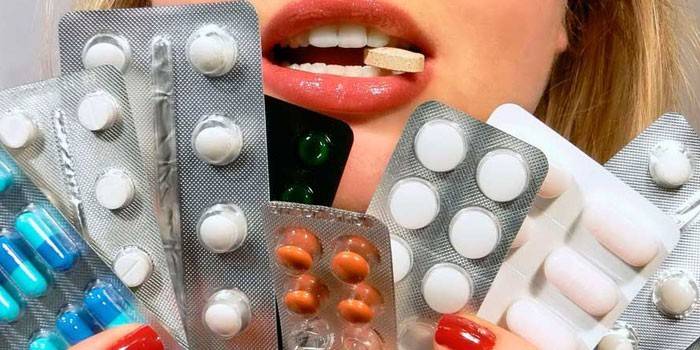 Pastillas y cápsulas en manos de una niña.