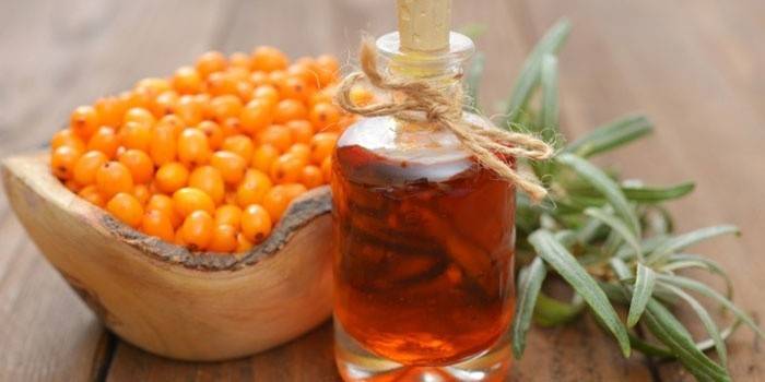 Óleo de espinheiro mar em uma garrafa e frutas de espinheiro mar