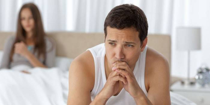 El chico está sentado en la cama en el dormitorio.