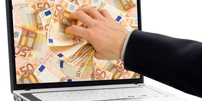 Laptop i ręka sięga po pieniądze