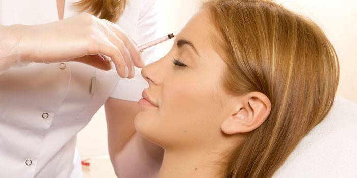 A esteticista dá injeções a uma menina hipodérmicamente