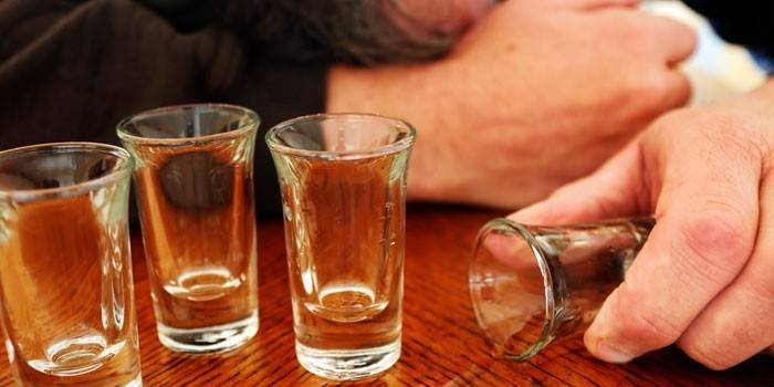 Vasos vacíos y un hombre durmiendo en la mesa