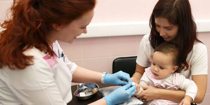 O médico realiza a coleta de sangue do dedo de uma criança