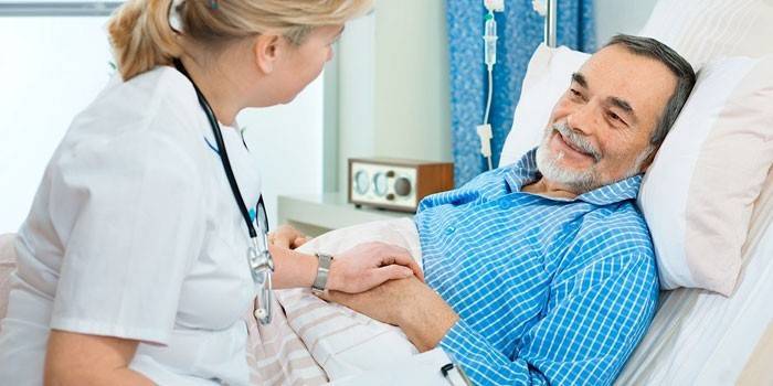 Médico al lado de la cama del paciente.