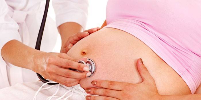 O médico ouve o batimento cardíaco fetal.