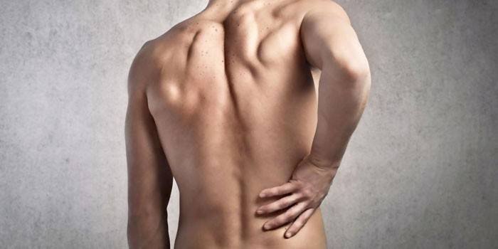 El hombre sostiene su mano sobre su espalda baja