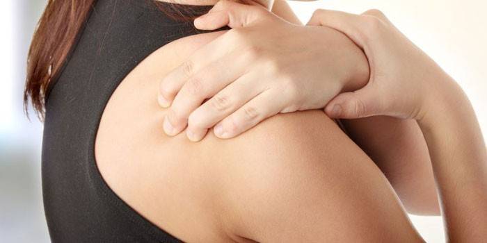 La mujer sostiene la mano en el hombro