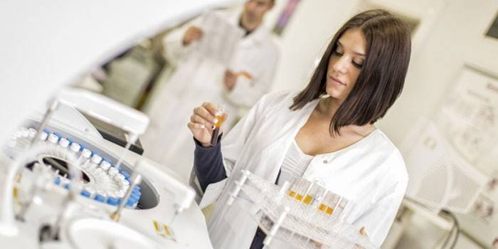 Técnico de laboratorio frente a una centrífuga con tubos de ensayo.