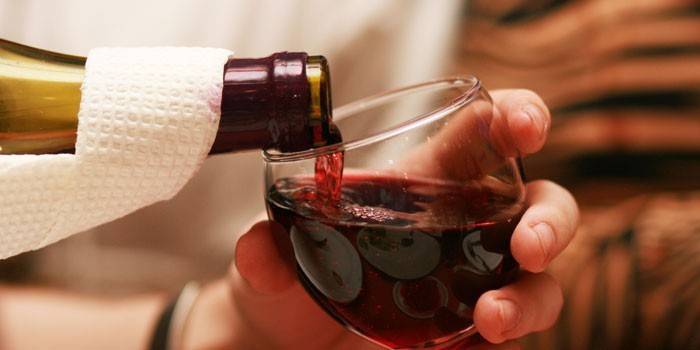 Czerwone wino wlewa się z butelki do szklanki