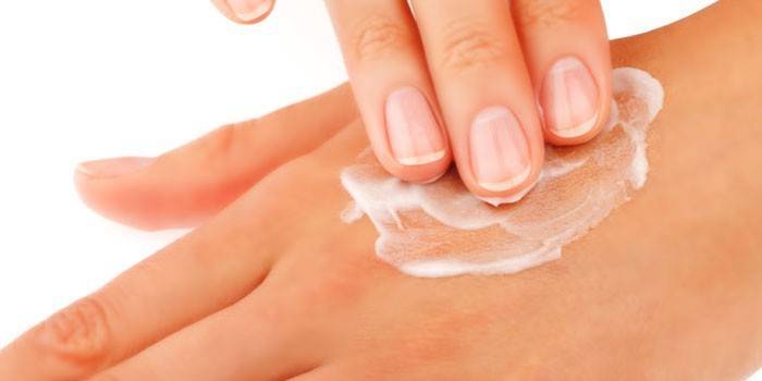 Chica unta las manos con crema