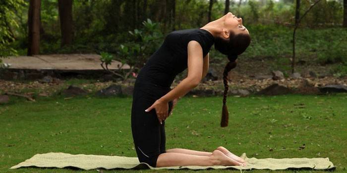 A menina está envolvida na ginástica tibetana na natureza