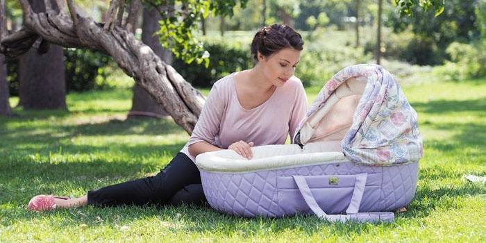 Kobieta z gondolą Happy Baby Charlotte w parku