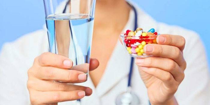 Comprimidos e um copo de água nas mãos de um médico
