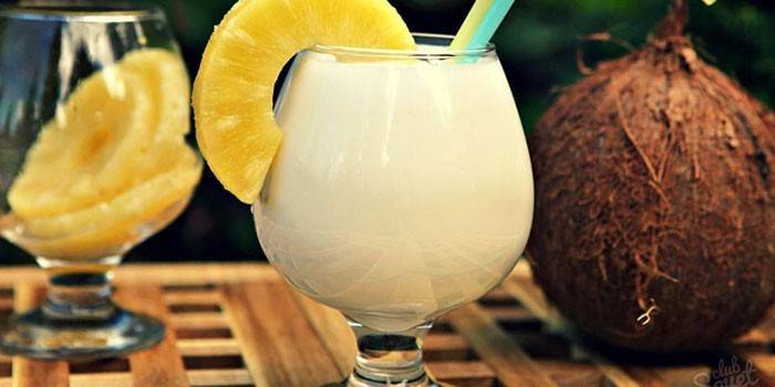 Coquetel em um copo com uma fatia de abacaxi e coco