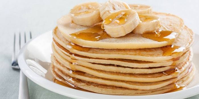 Una pila de panqueques con rodajas de plátano y miel