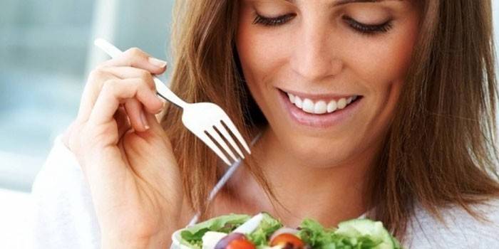 Garota tem um prato com salada e um garfo nas mãos dela