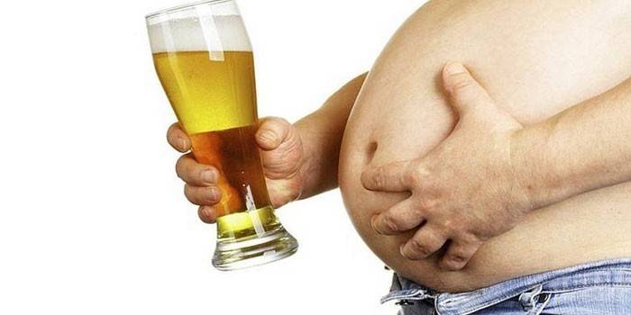 Mužský žalúdok a pohár piva v ruke