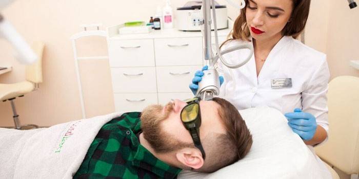 Medic vykonáva laserové odstránenie névusu na tvári človeka