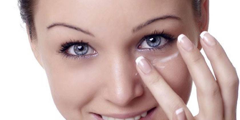 Chica pone crema debajo de los ojos