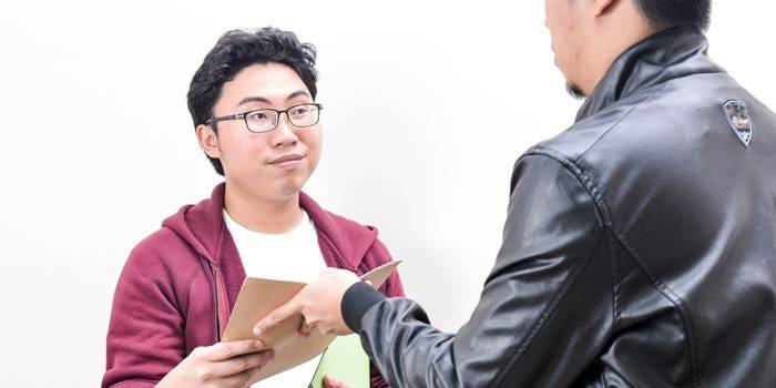 Um homem passa documentos para outra pessoa