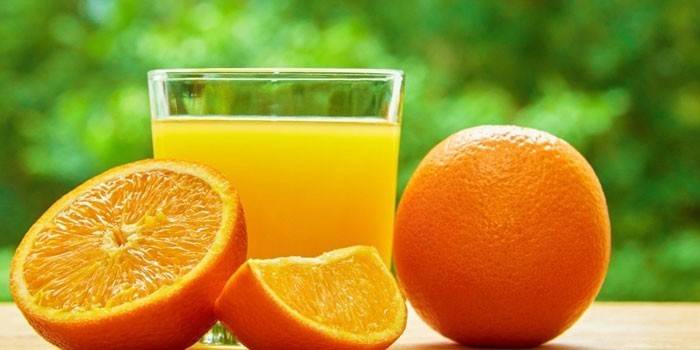 Sok pomarańczowy w szklance i pomarańczach
