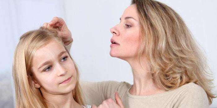 Uma mulher examina a cabeça de uma menina