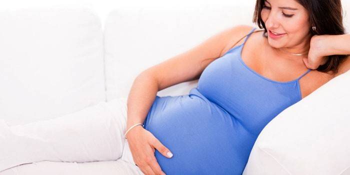 La niña embarazada yace en un sofá