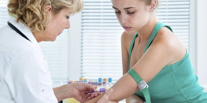 Medic vykonáva odber krvi z dievčenskej žily