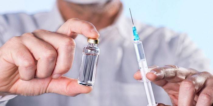 Seringa e droga em uma garrafa nas mãos de um homem