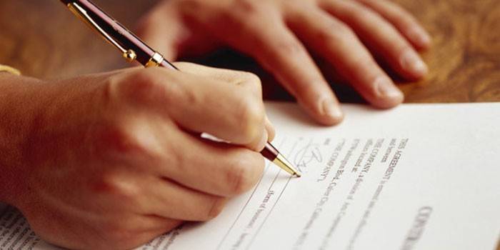 El hombre firma un contrato.