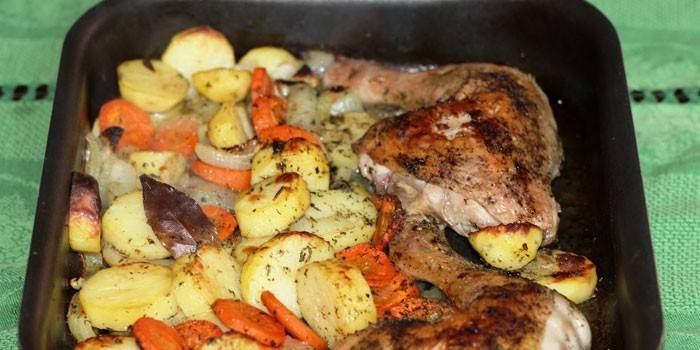 Pernas de frango assado com batatas e legumes em uma assadeira
