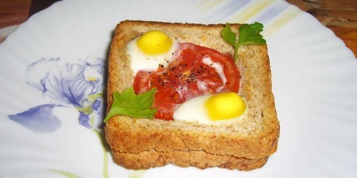 Sandwich caliente con huevos de codorniz y tomate en un plato