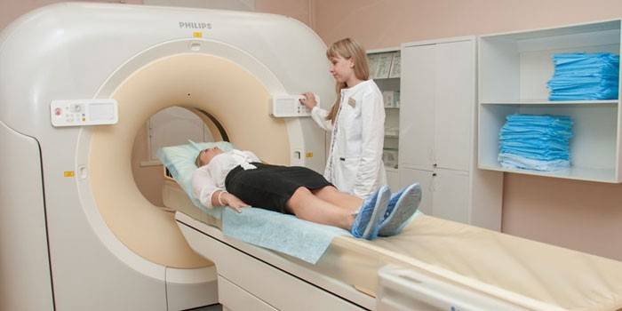 Chica en un aparato de tomografía computarizada y un médico cercano
