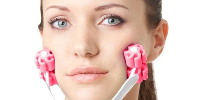 Garota faz massagem facial com um massageador.
