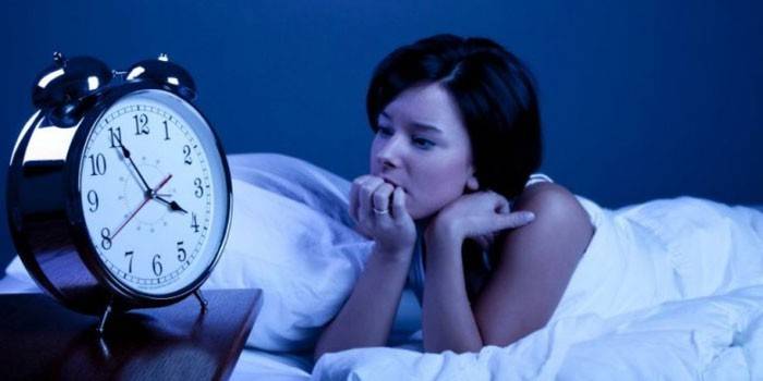 Chica en la cama y un despertador