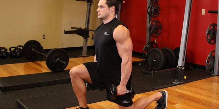 Mężczyzna robi rzuca się z dumbbells w gym