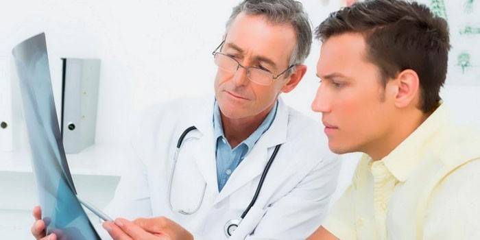 El médico le muestra al paciente radiografías.