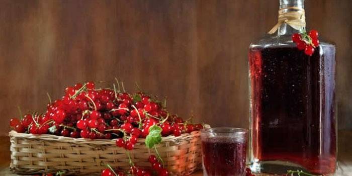 Wino z czerwonej porzeczki w butelce i porzeczka w koszu