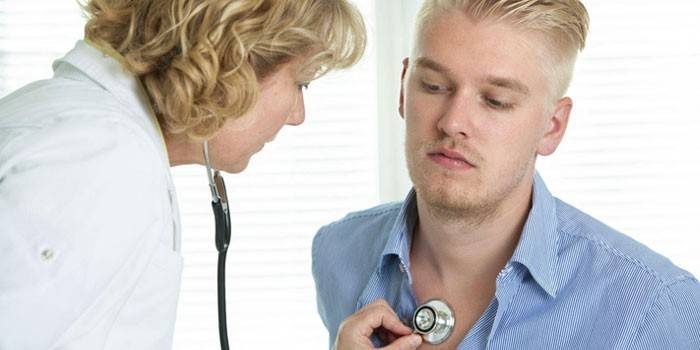 O médico ouve os brônquios do cara com um estetoscópio