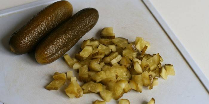 Encurtidos en rodajas y enteros en una tabla de cortar