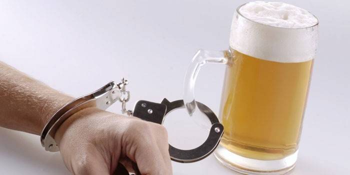 Um copo de cerveja algemada a uma mão