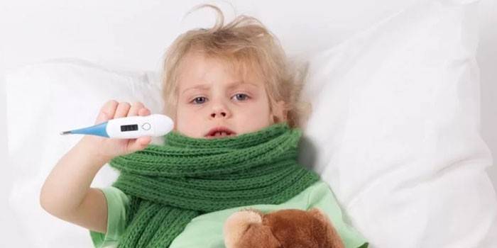 Dieťa leží v posteli a drží v ruke elektronický teplomer