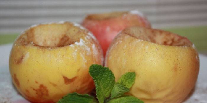 Trzy pieczone jabłka z cukrem pudrem na talerzu