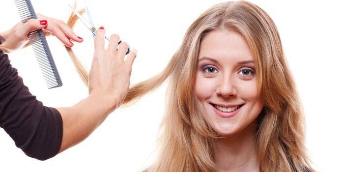 O cabeleireiro corta o cabelo da menina