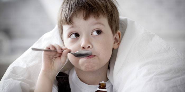 Un niño bebe jarabe de una cuchara