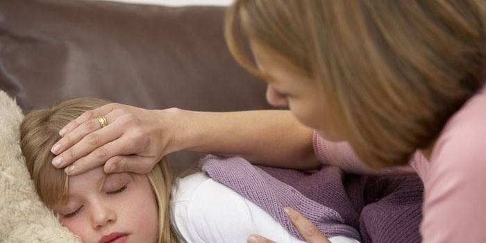 Ręką kobieta mierzy temperaturę śpiącej dziewczyny