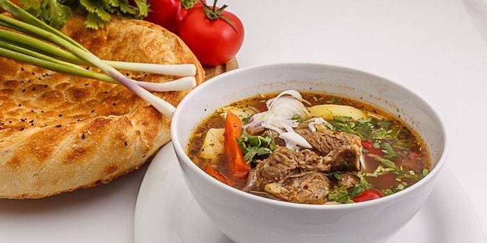 Shurpa em um prato e pão pita com legumes