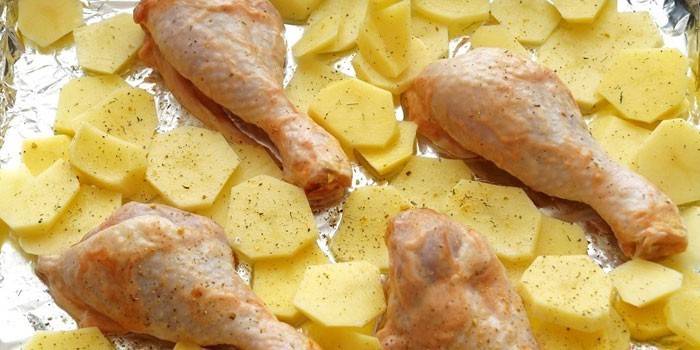 Zemiakové plátky a kuracie paličky na pleche pred pečením